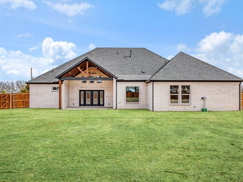 Back of property featuring a patio area, french doors, roof with shingles, brick siding, and a fenced backyard