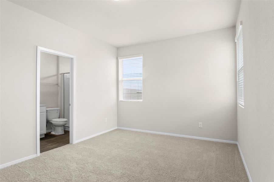 Unfurnished bedroom featuring carpet, multiple windows, and ensuite bath Unfurnished bedroom featuring carpet, multiple windows, and ensuite bath