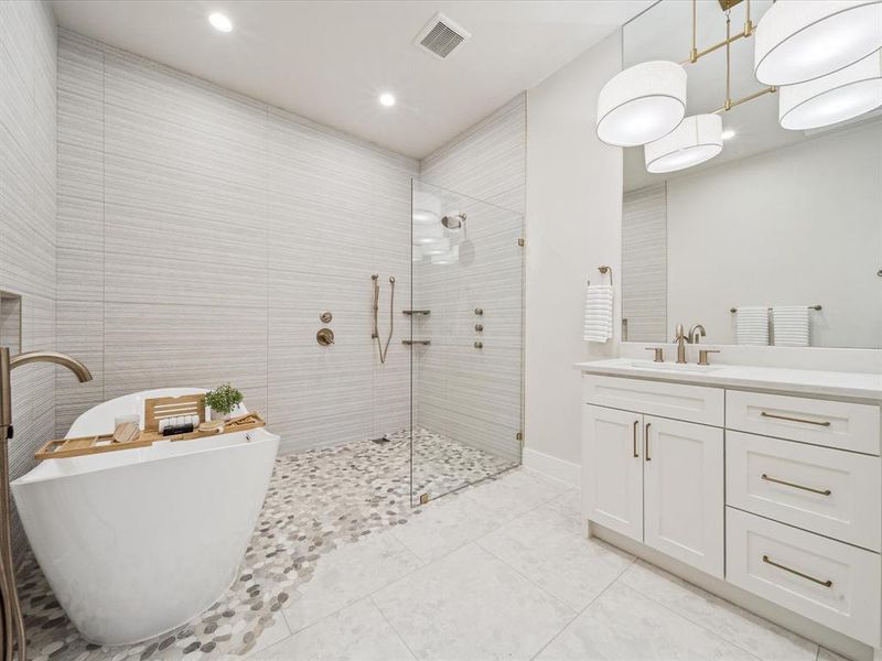 Bathroom featuring shower with separate bathtub, vanity, and tile walls