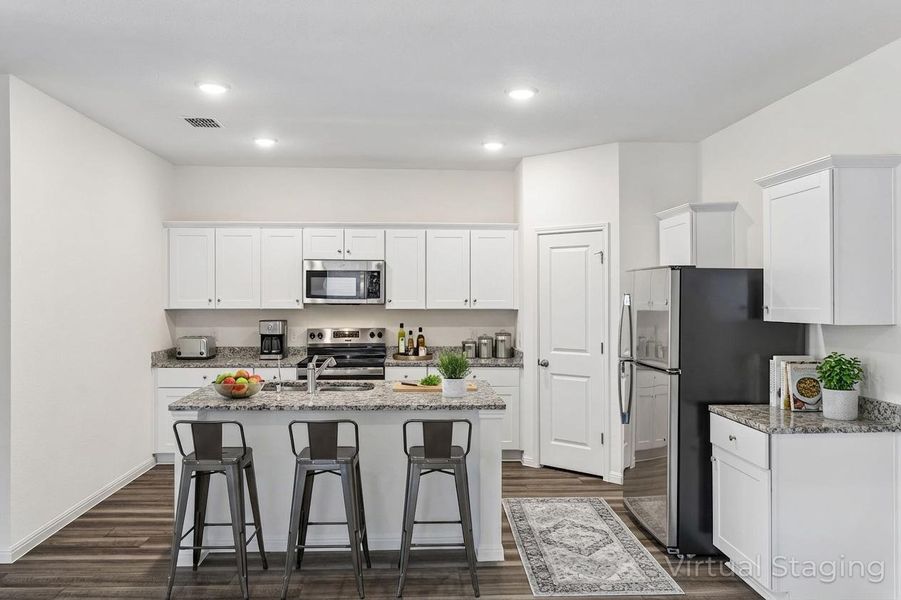 Kitchen featuring white cabinetry, stainless steel appliances, light stone countertops, a center island with sink, and recessed lighting