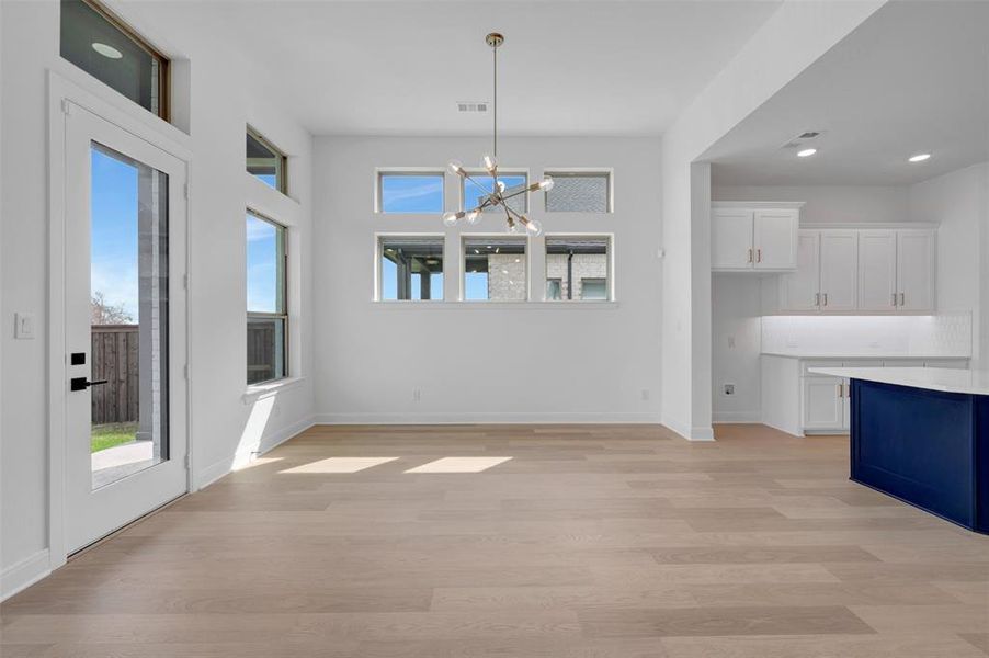 Unfurnished dining area with suspended lighting, light wood finished floors, and plenty of natural light