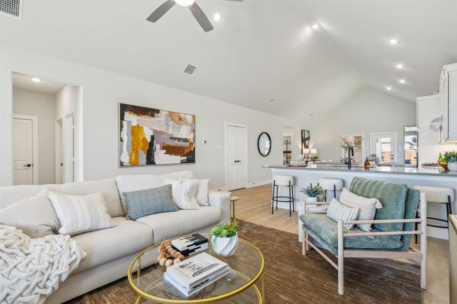 Living room with light hardwood / wood-style floors, ceiling fan, and vaulted ceiling