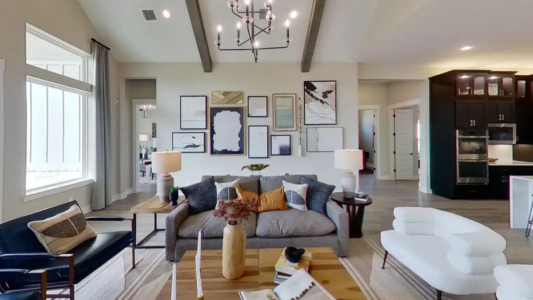 Living room with hanging lights, light wood-style flooring, and vaulted ceiling with beams