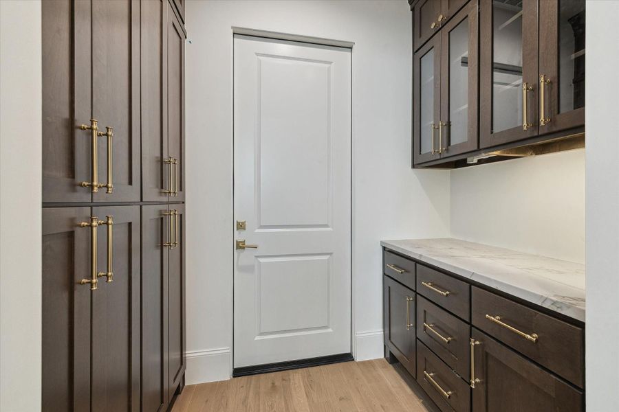 Off the kitchen is the pantry with excessive vertical cabinetry, as well as secondary space with countertop and glass-face cabinetry above to use as storage, additional prep space, or a dry bar area!