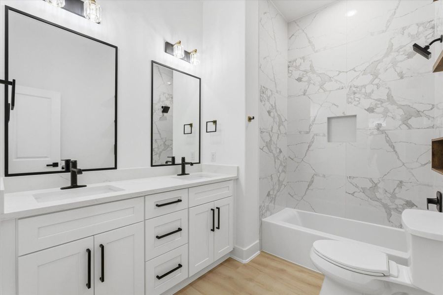 A third full bathroom featuring dual sinks and a practical shower/tub combination.