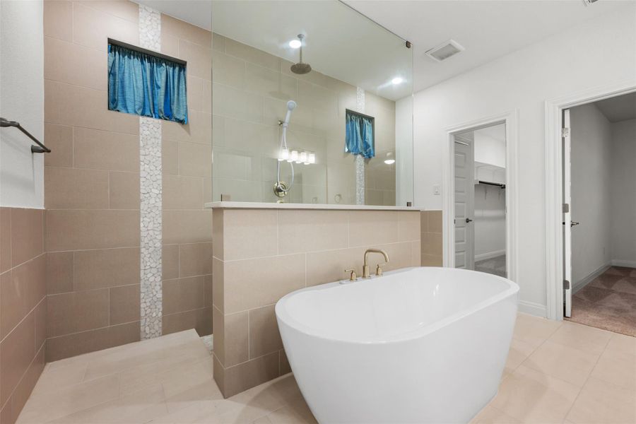 Full bathroom featuring walk in shower, a walk in closet, tile patterned flooring, and a freestanding bath Full bathroom featuring walk in shower, a walk in closet, tile patterned flooring, and a freestanding bath
