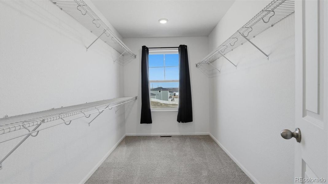 Huge walk in closet with built-in racks and window in the Primary Bedroom.