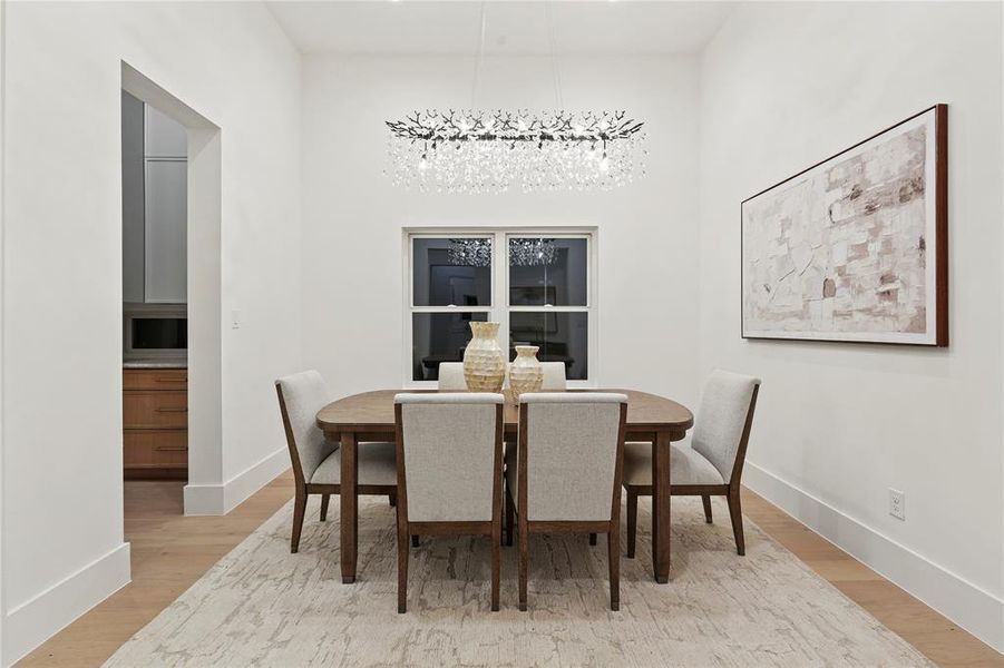 Dining room featuring light wood-style flooring, a towering ceiling, and a chandelier