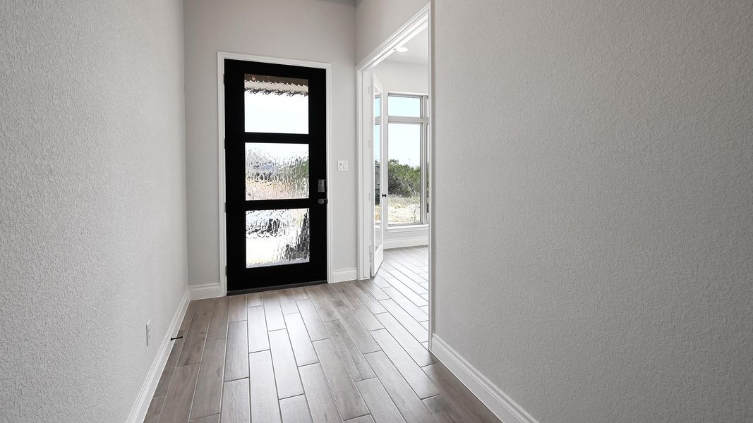 Entryway with baseboards, a textured wall, and wood finished floors Entryway with baseboards, a textured wall, and wood finished floors