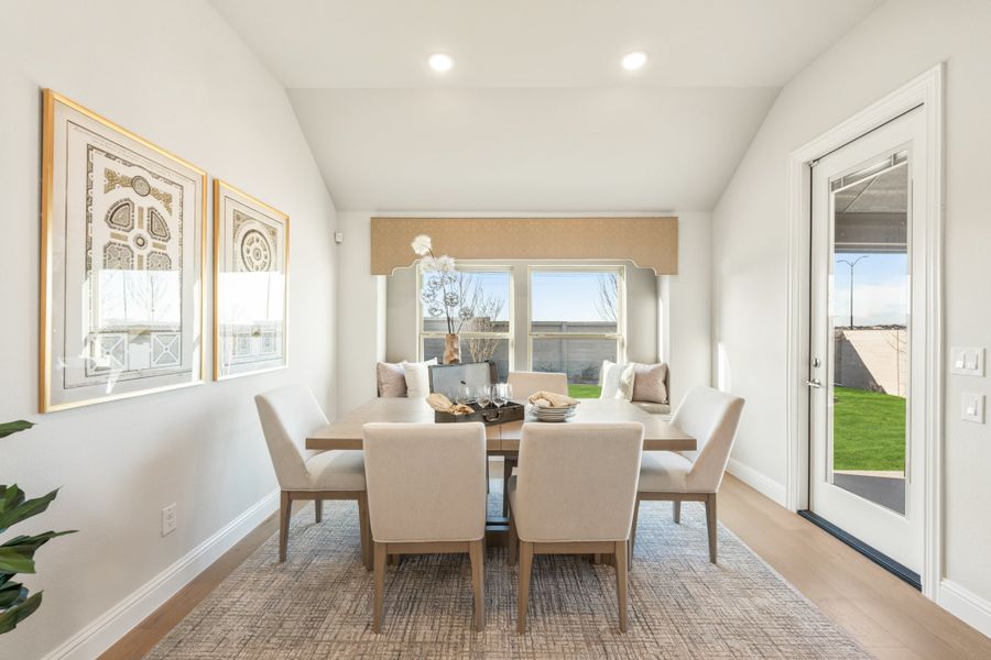 Dining room with six-chair table, vaulted ceiling, window seat, and glass door to backyard