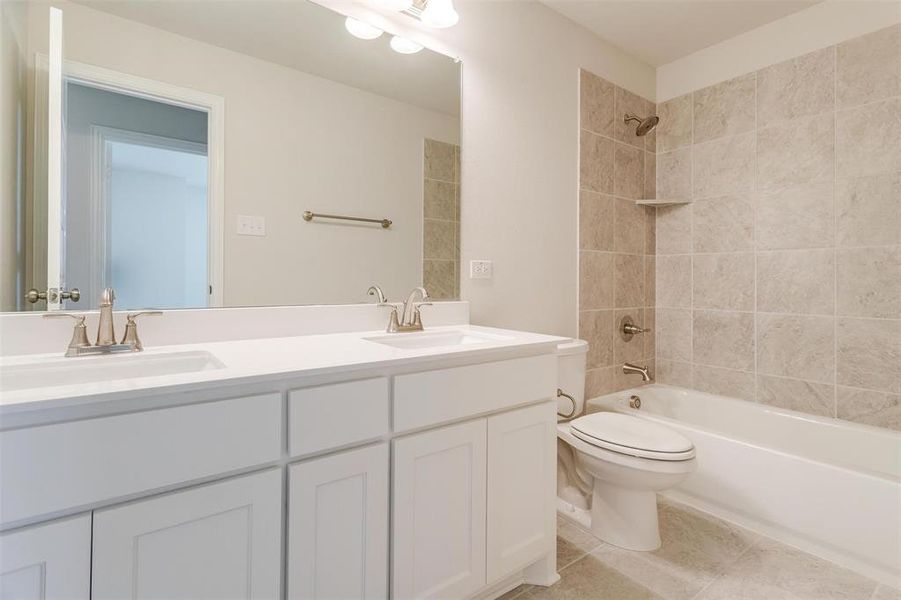 Full bathroom featuring tiled shower / bath, vanity, toilet, and tile patterned floors Full bathroom featuring tiled shower / bath, vanity, toilet, and tile patterned floors