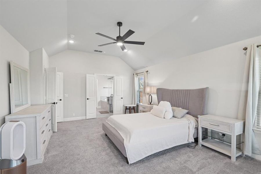 Bedroom featuring lofted ceiling, light carpet, ensuite bathroom, and a ceiling fan Bedroom featuring lofted ceiling, light carpet, ensuite bathroom, and a ceiling fan