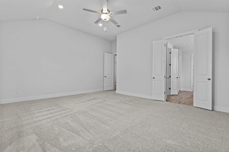 Unfurnished bedroom with vaulted ceiling, ceiling fan, and light carpet