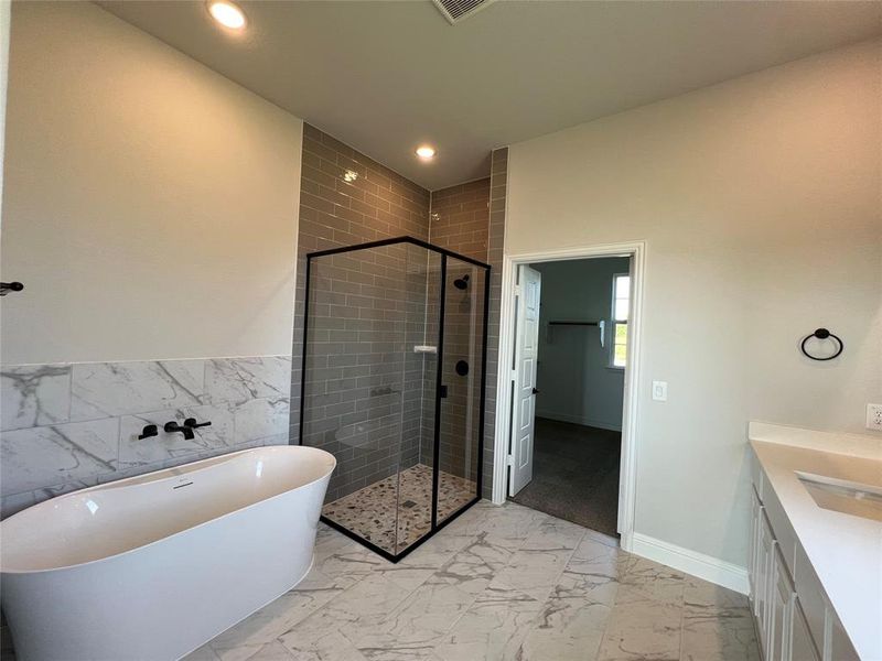 Bathroom featuring vanity, a shower stall, a freestanding tub, light marble finish floors, and recessed lighting