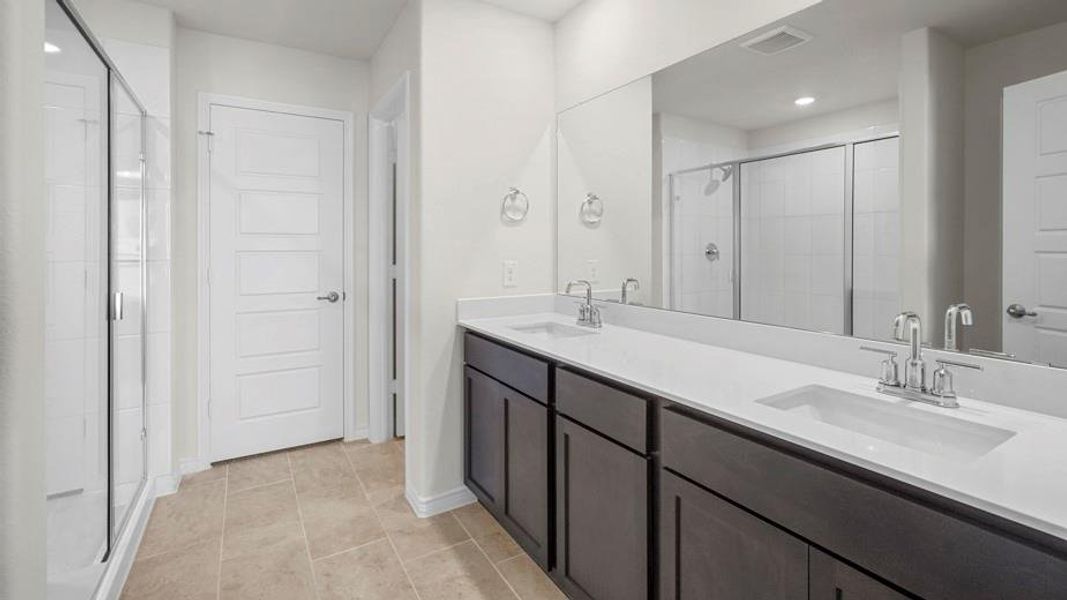 The bathroom features a dual vanity with dark cabinetry and a light-colored countertop, along with a large mirror