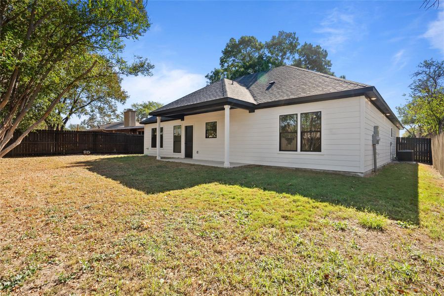 Rear view of house with a patio, a fenced backyard, and a shingled roof