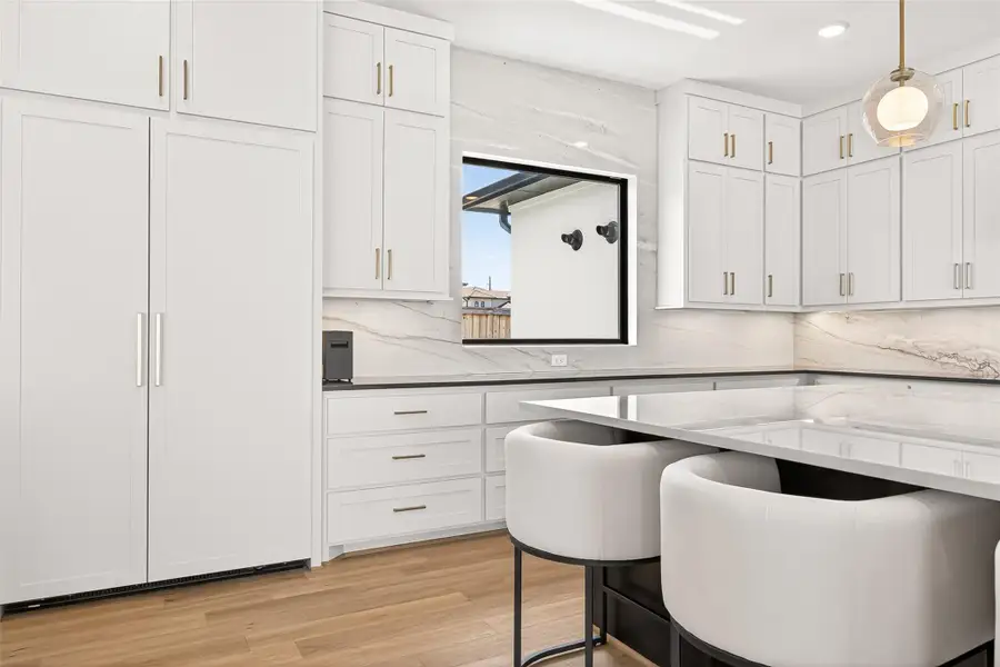 Hidden paneled refrigerator, Quartzite backsplash walls, black granite countertops, stacked shaker-style cabinetry, under-cabinet lighting, soft-close drawers, hidden pull-out trash storage, pot drawers, and dual disposal switches complete this exceptional culinary space.