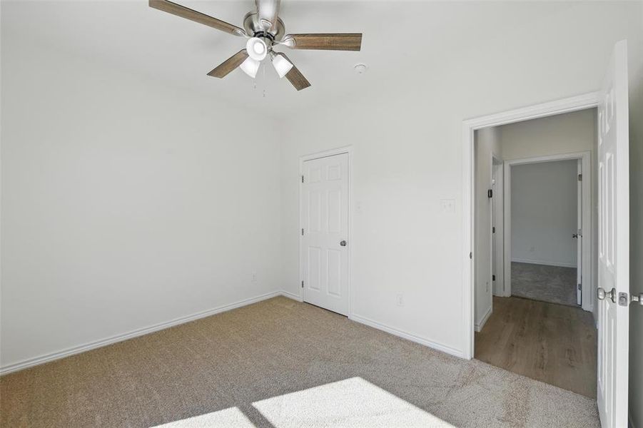 Carpeted spare room with ceiling fan and baseboards Carpeted spare room with ceiling fan and baseboards
