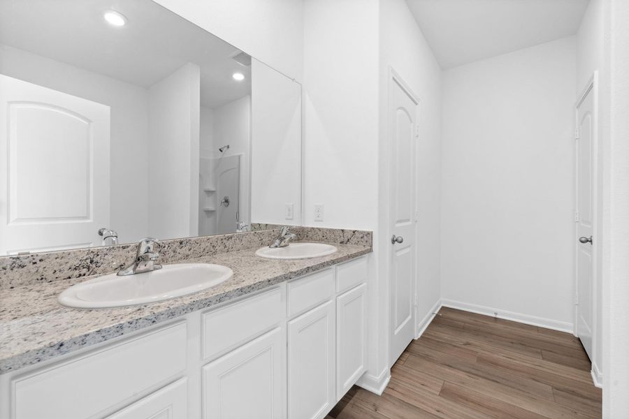 Bathroom featuring double vanity, a stall shower, light wood-type flooring, and recessed lighting