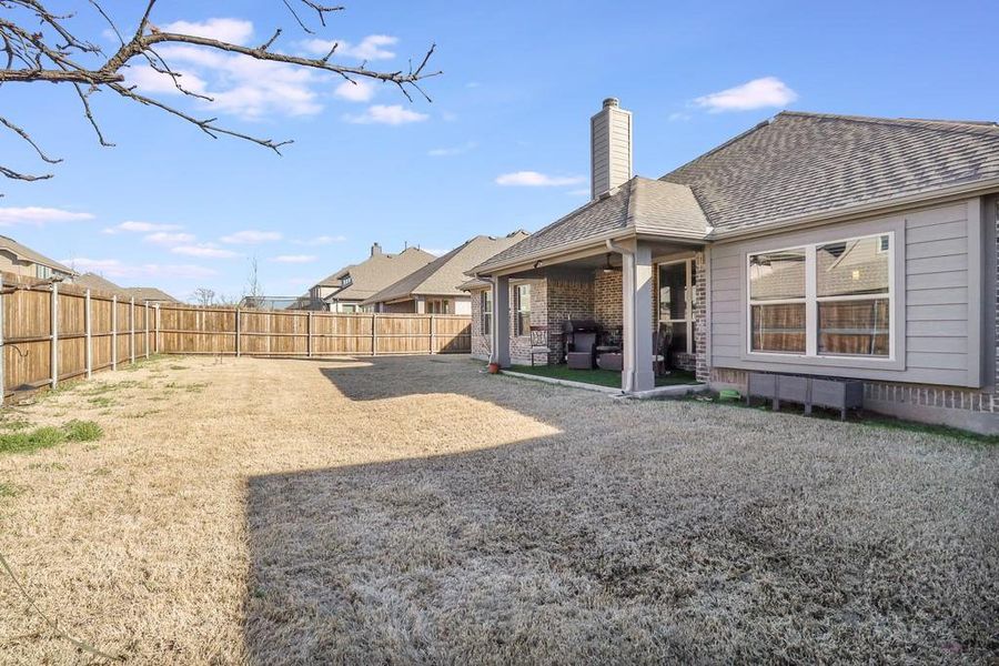 Rear view of house with a patio area, a chimney, a fenced backyard, and roof with shingles Rear view of house with a patio area, a chimney, a fenced backyard, and roof with shingles