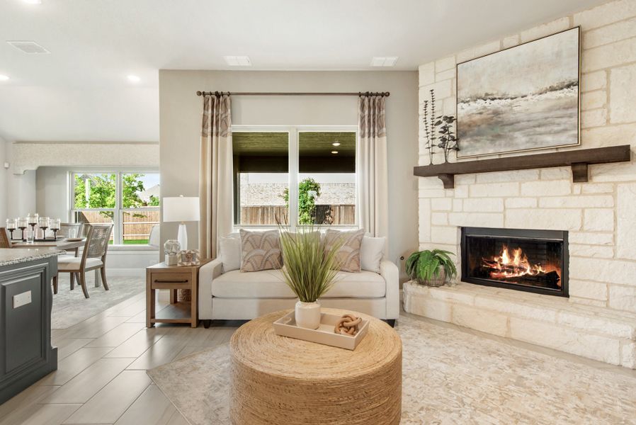 Living room with stone fireplace, white sofa, and round woven coffee table open to dining area