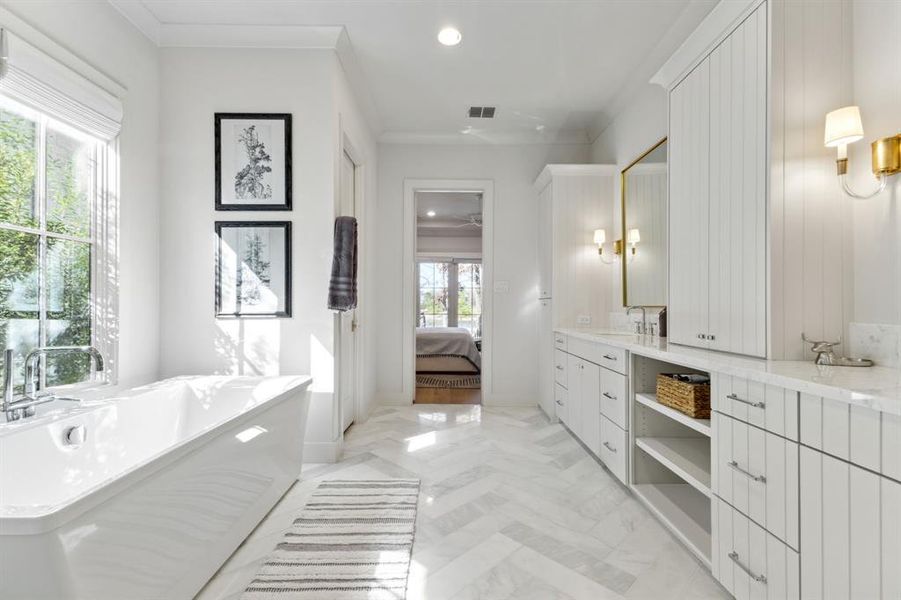 Full bath featuring connected bathroom, ornamental molding, a freestanding bath, vanity, and recessed lighting Full bath featuring connected bathroom, ornamental molding, a freestanding bath, vanity, and recessed lighting