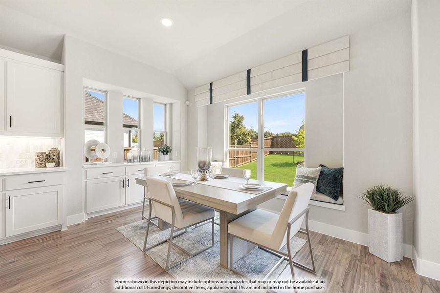 Bright dining area with wood floors, window seat, and large windows overlooking backyard
