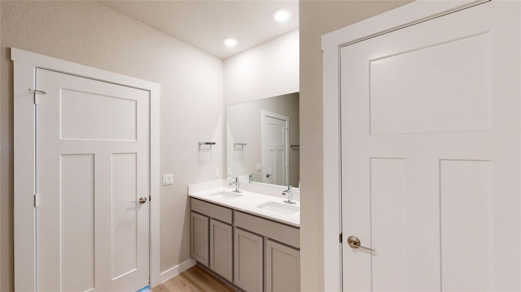 Bathroom with double vanity, light wood-type flooring, and recessed lighting