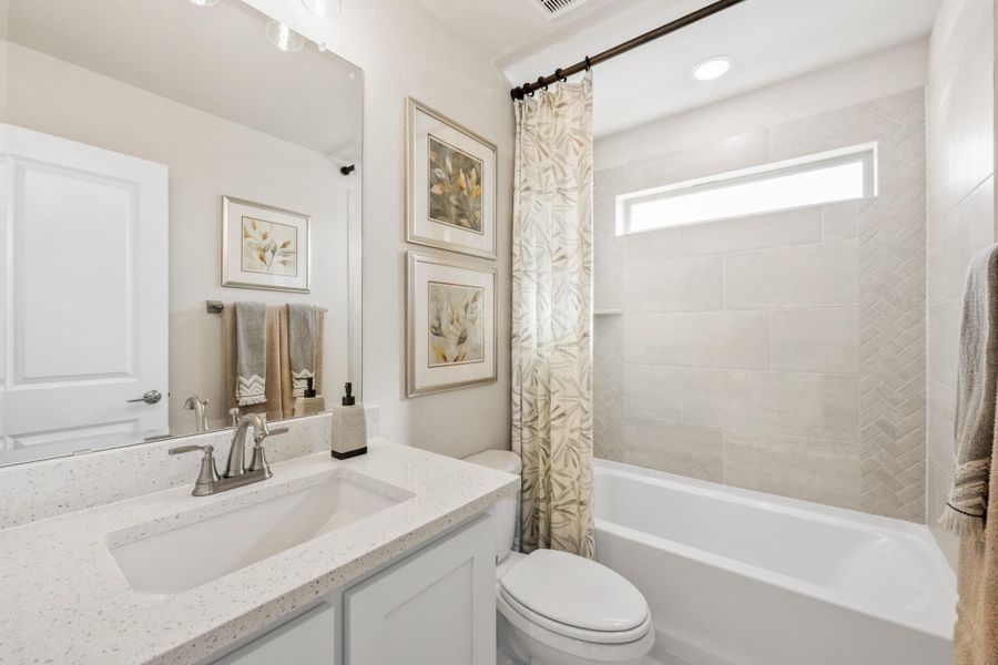 Full bathroom with quartz vanity, white cabinets, and tiled tub-shower combo with curtain Full bathroom with quartz vanity, white cabinets, and tiled tub-shower combo with curtain