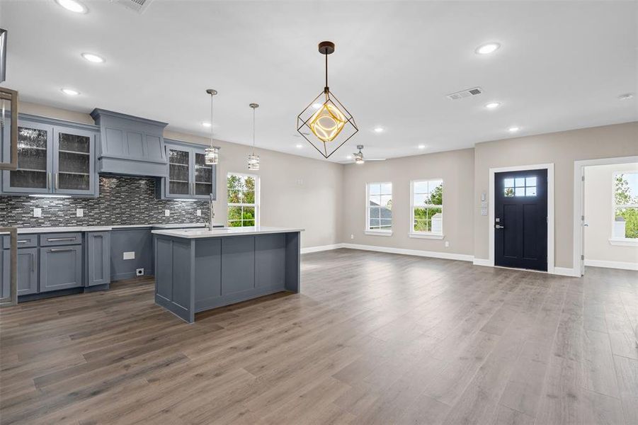 Kitchen with glass insert cabinets, healthy amount of natural light, hanging light fixtures, gray cabinets, and recessed lighting Kitchen with glass insert cabinets, healthy amount of natural light, hanging light fixtures, gray cabinets, and recessed lighting