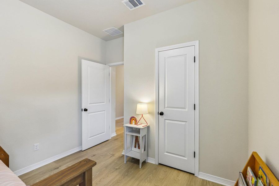Blonde hardwood-style flooring extends through this inviting bedroom, featuring two paneled doors.