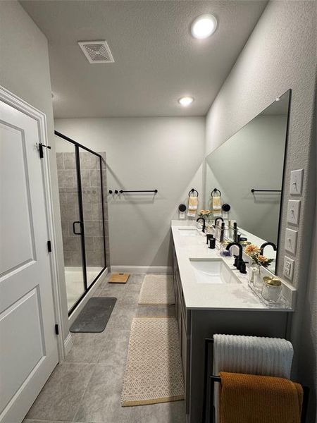 Full bathroom featuring a shower stall, double vanity, a textured ceiling, light tile patterned floors, and recessed lighting Full bathroom featuring a shower stall, double vanity, a textured ceiling, light tile patterned floors, and recessed lighting