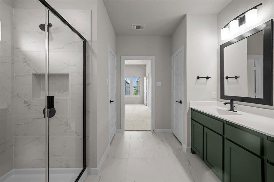 Full bathroom with light marble finish floors, a marble finish shower, and vanity