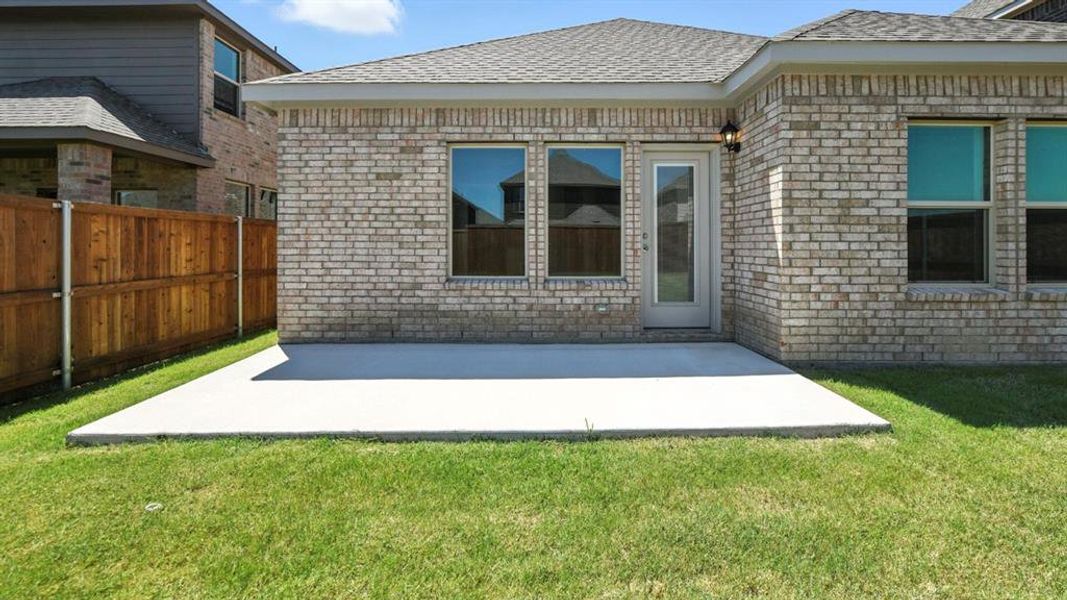 Rear view of house featuring brick siding, a patio area, and a shingled roof