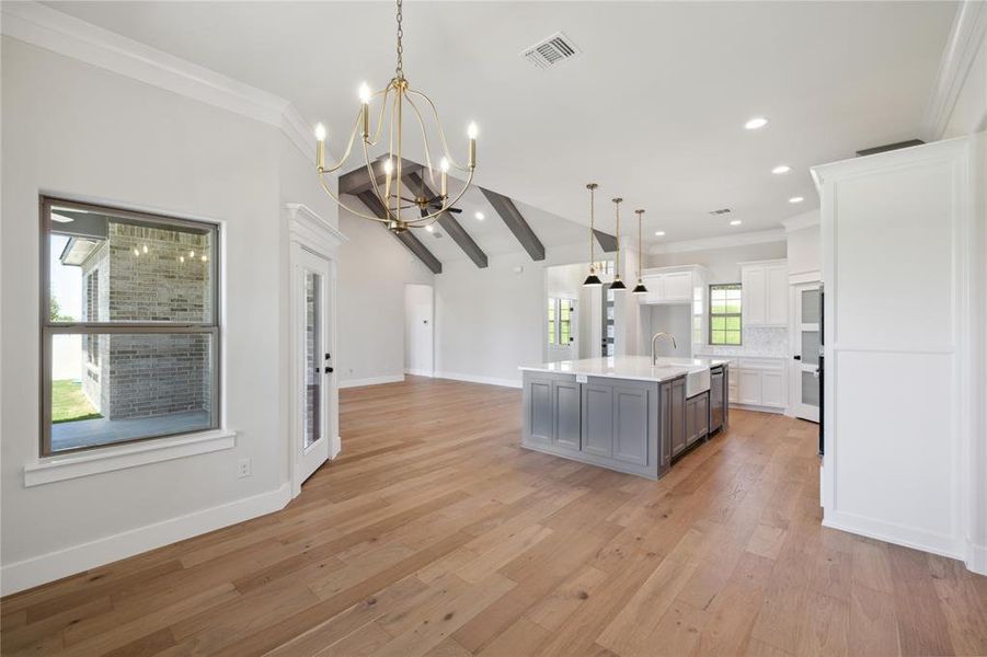 Kitchen with a wealth of natural light, light hardwood / wood-style floors, white cabinetry, and a center island with sink