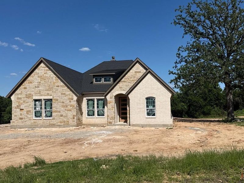 Stone and brick exterior with dark shingle roofing