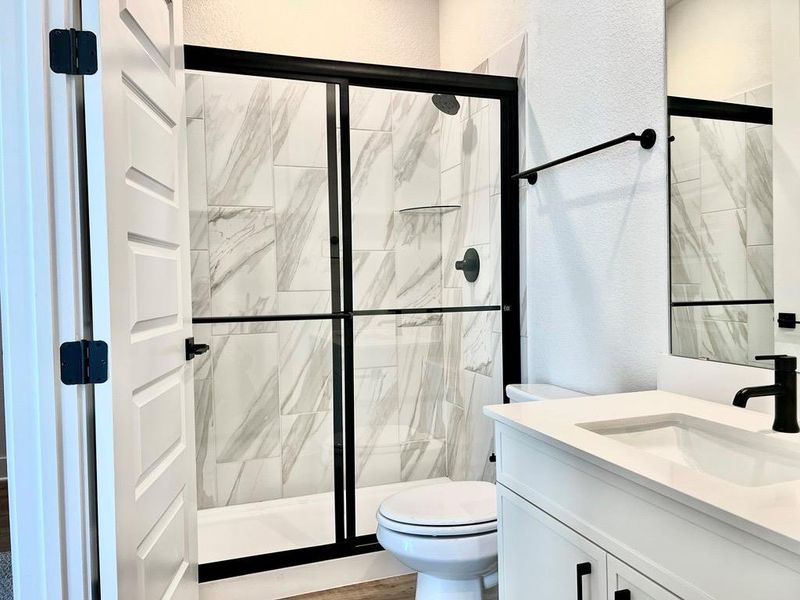 Bathroom featuring a textured wall, vanity, and a marble finish shower