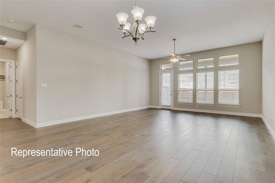 Unfurnished room featuring hardwood / wood-style floors and ceiling fan with notable chandelier