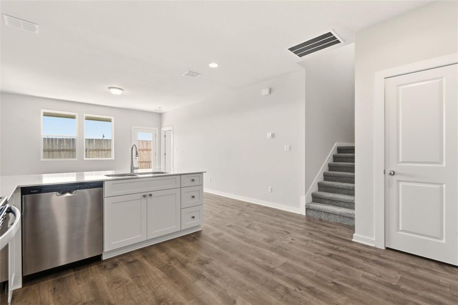 Kitchen featuring appliances with stainless steel finishes, white cabinetry, recessed lighting, dark wood-type flooring, and light stone countertops
