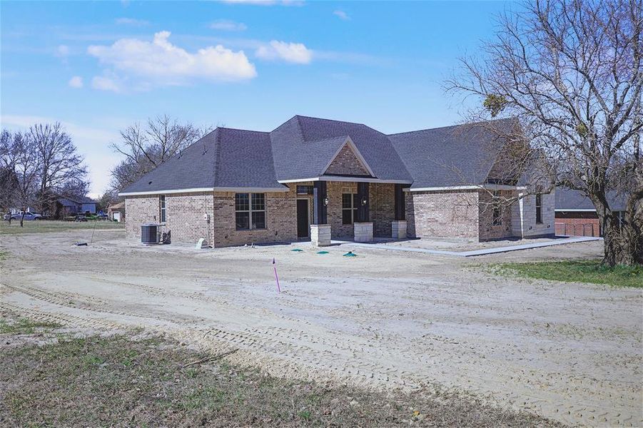 View of front of property with brick siding, roof with shingles, and a porch