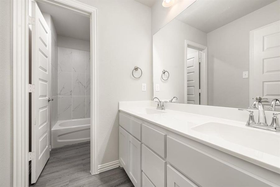 Bathroom featuring dual vanity, tiled shower / bath, and hardwood / wood-style flooring