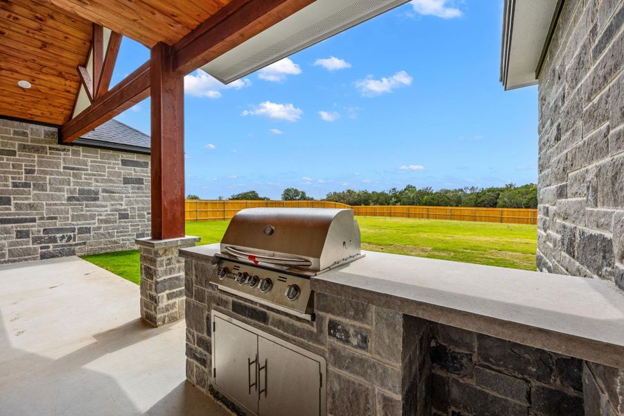 Fenced backyard featuring a patio area and exterior kitchen