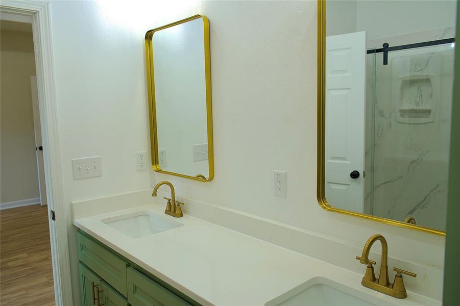 Bathroom featuring double vanity, wood finished floors, and a marble finish shower