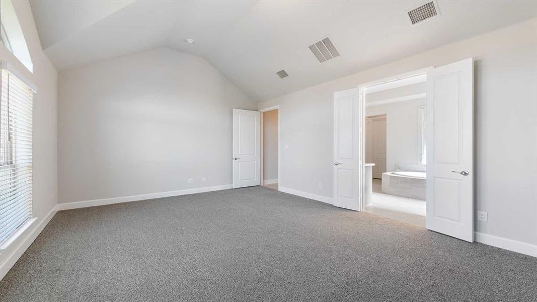 Unfurnished bedroom with carpet flooring and lofted ceiling