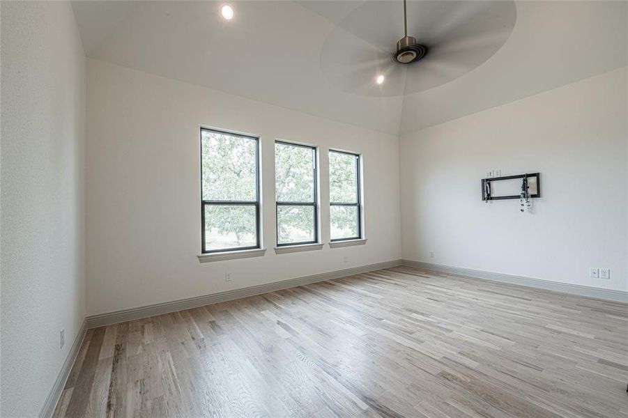 Unfurnished room featuring light wood-type flooring, ceiling fan, lofted ceiling, and recessed lighting Unfurnished room featuring light wood-type flooring, ceiling fan, lofted ceiling, and recessed lighting