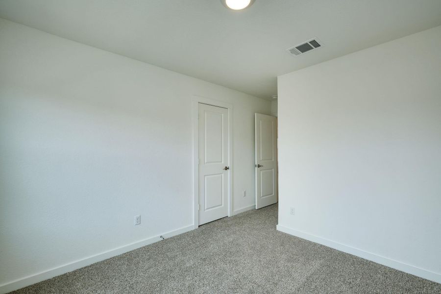 Carpeted spare room featuring visible vents and baseboards