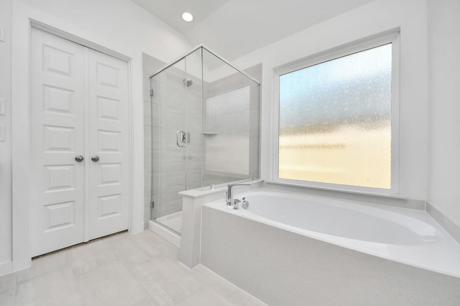 Indulge in a spa-like retreat within the confines of this primary bathroom. Delight in a spacious walk-in shower enveloped in stylish tile surround, unwind in a separate garden tub adorned with custom detailing.