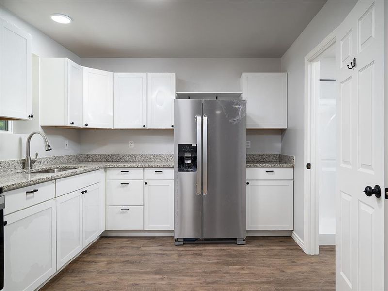 Kitchen with white cabinets, stainless steel fridge, and dark wood-type flooring
