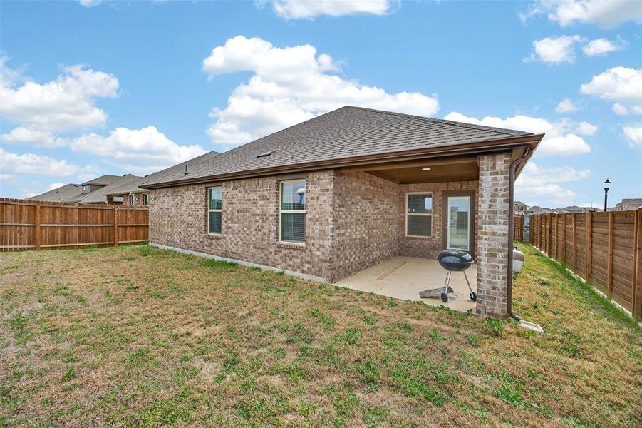 Rear view of house with a fenced backyard, a shingled roof, a patio area, and brick siding