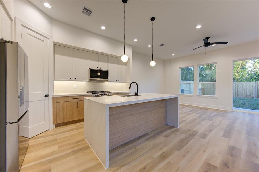 This stunning kitchen features upgraded quartz countertops (2" thick laminated edges), large pantry, waterfall island, sleek modern cabinetry, and stainless steel smart appliances, including the craft ice refrigerator!